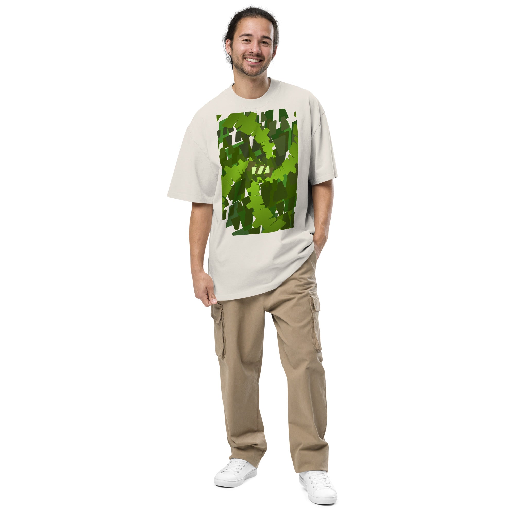 Product mockup of a man wearing a faded bone colored, oversized tshirt with a Brekky Design on the front. The design is "Emerald Stream": geometric shapes (made by the Brekky Logo) placed painterly to create a green swirl..